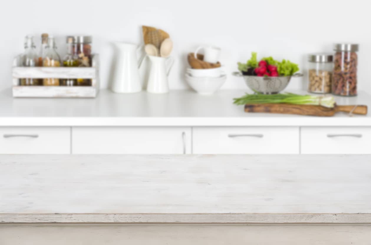 Wooden-table-on-blurred-kitchen-interior-background-with-fresh-vegetables-647234646_1261x835
